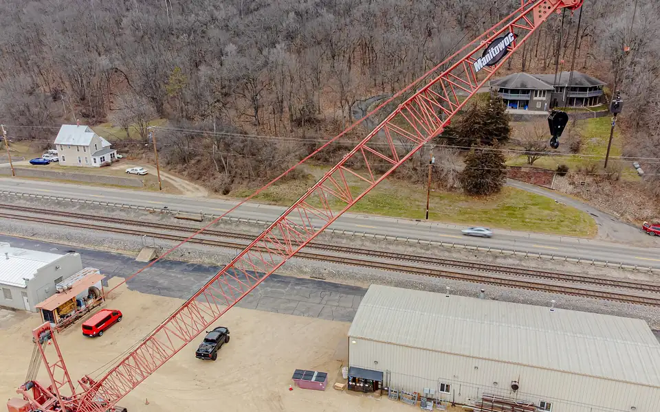 Lattice-boom crawler crane working beside a railway yard